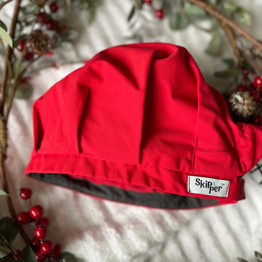 Red shower cap with 'Skipper' label on a white surface with greenery