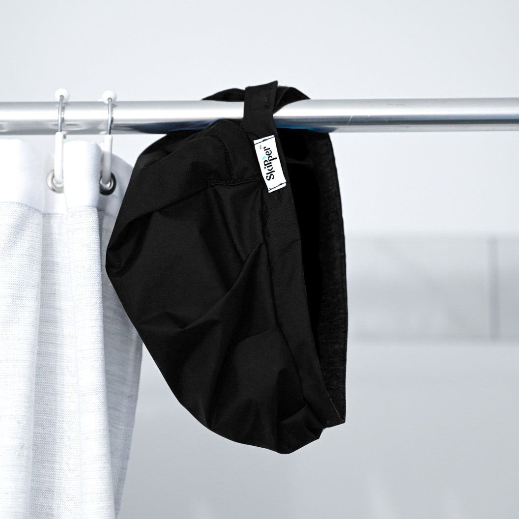 Skipper shower cap in black hanging from shower curtain rod