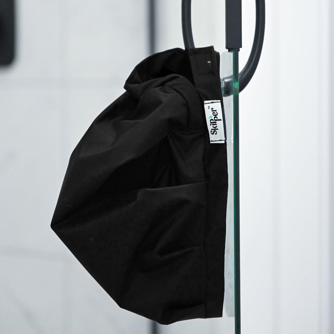 Skipper shower cap in black, hanging to dry on shower handle